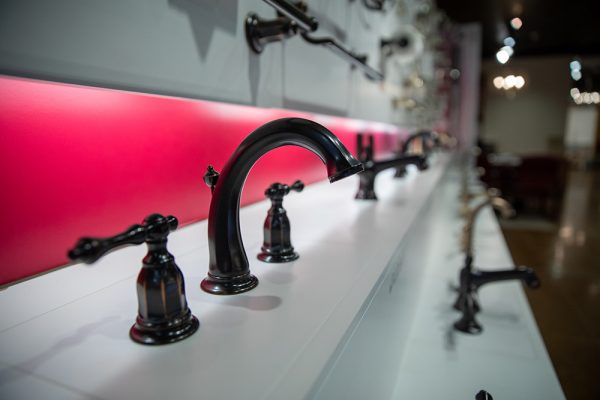 Closeup image of black bathroom sink faucet with red wall in background
